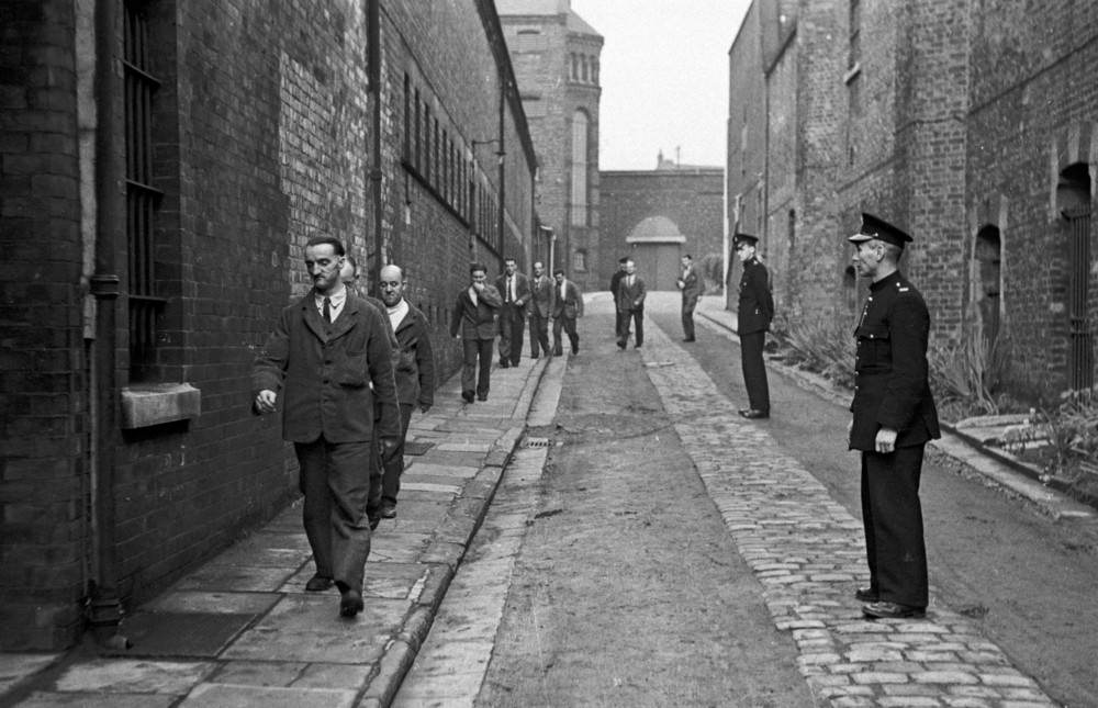 Prison officers watching prisoners return from their daily outdoor exercise at Strangeways Prison.