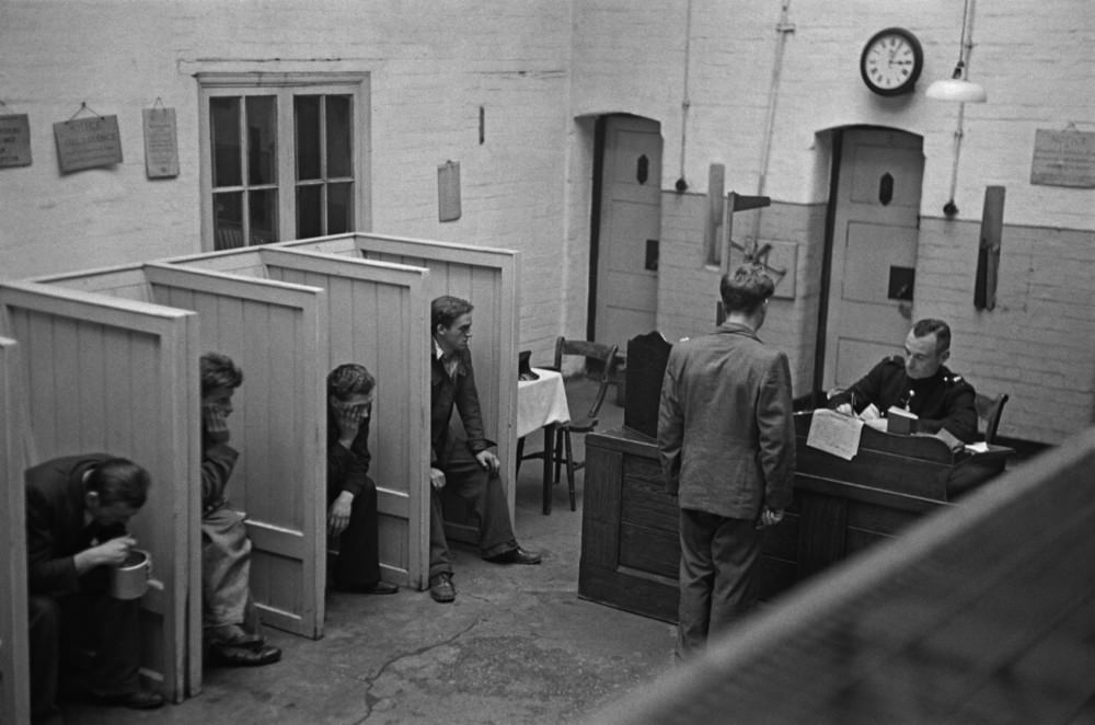 Prison officer Davidson interviewing a group of new prisoners in the reception room at Strangeways Prison.