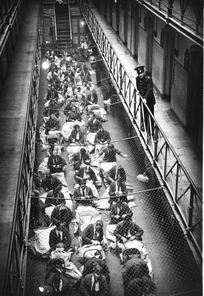 A prison officer watches over prisoners who are busy sewing mailbags in Strangeways Prison.