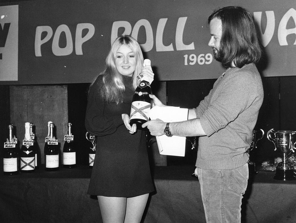 Mary Hopkin, who took second place in the Melody Maker Poll for the best girl singer, is awarded a bottle of champagne by John Peel, 1969.