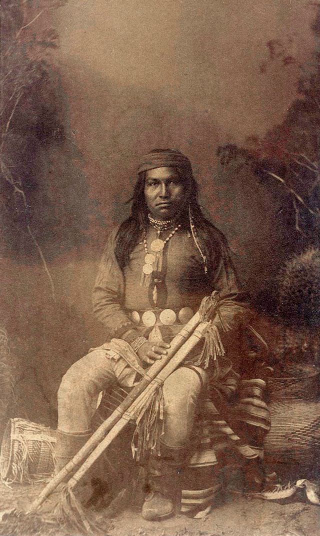 Apache warrior seating and holding a sheathed bow and arrow quiver