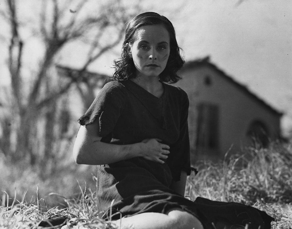 Paulette Goddard wearing rags and sitting on the ground, 1936.