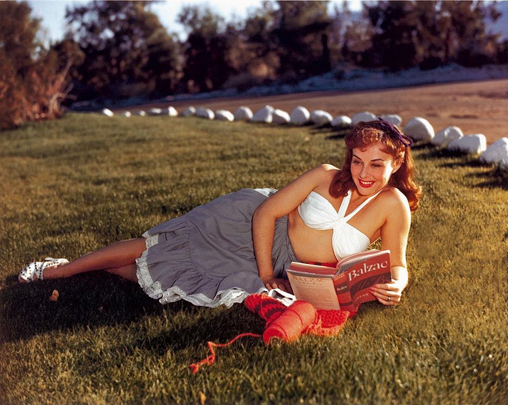 Paulette Goddard reading a book in the park, 1940.