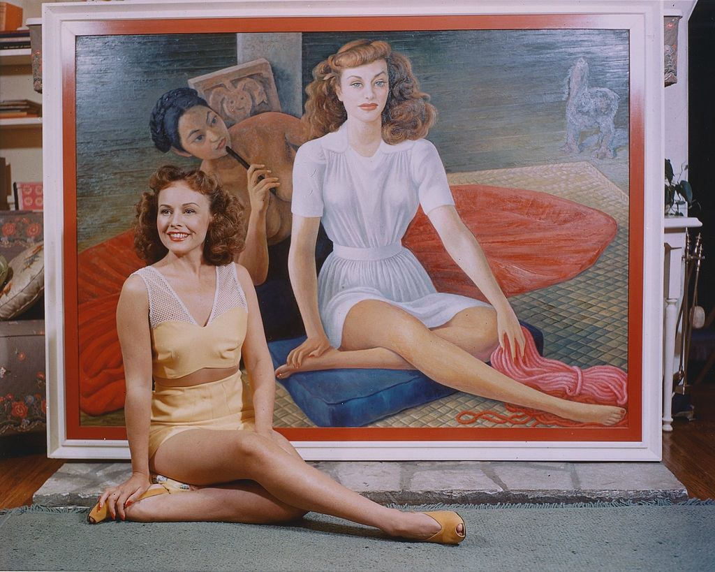 Paulette Goddard sitting on the floor alongside a portrait of herself, painted by the Mexican artist, Diego Rivera, 1940.