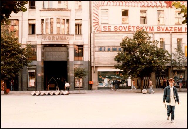 Barrels of beer are rolled to the front of the Koruna hotel under a sign extolling the virtues of state socialism