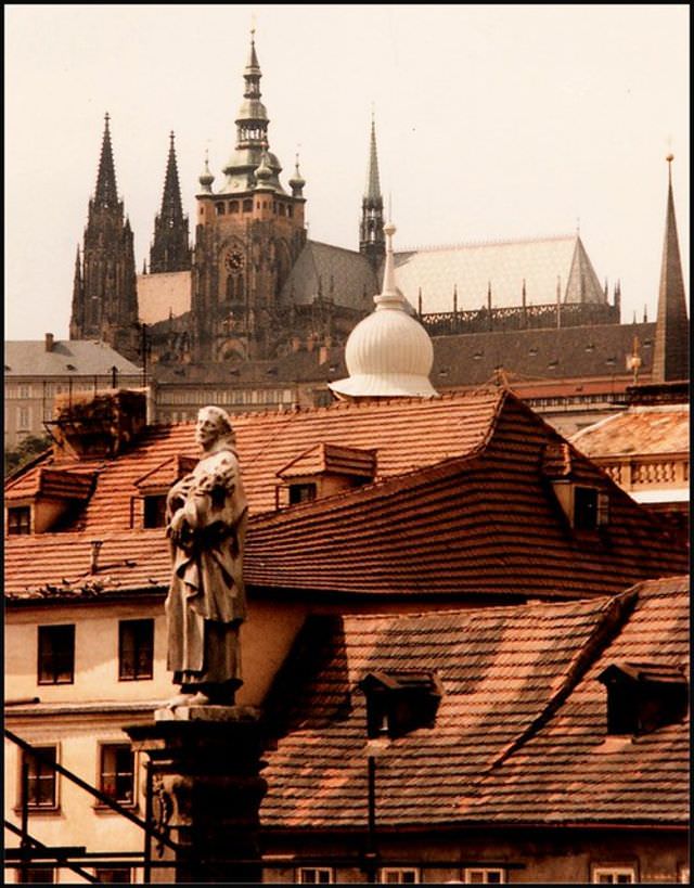 St. Vitus Cathedral peeps above the houses of Malé Strana, with the Charles Bridge statue of St Philip Benizi in the foreground
