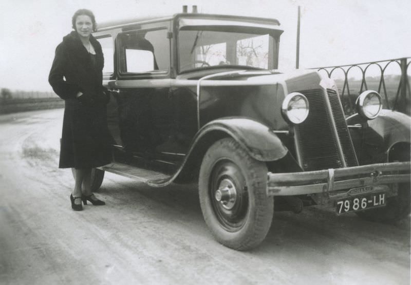 A lady in a black fur-collared coat posing with a Renault Monasix on a bleak winter's day.