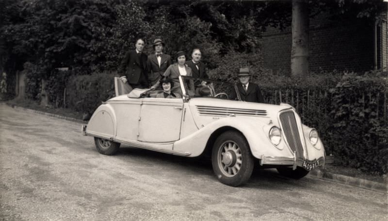 Two ladies and four gents posing with a Renault Viva Grand Sport Cabriolet. The car is registered in the city of Paris, July 9, 1939