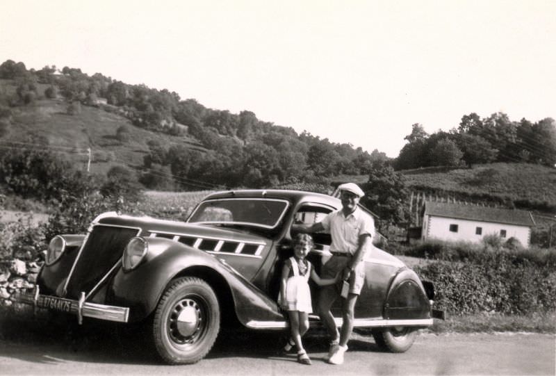 A father and his daughter posing with a Renault Viva Grand Sport Coupé in the countryside. The car is registered in the city of Paris, 1950
