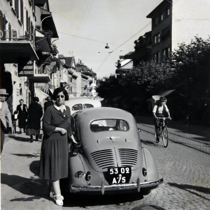 Lady posing with a Renault 4 CV in a cobbled street in the Swiss city of Thun. The car is registered in the city of Paris, August 1951