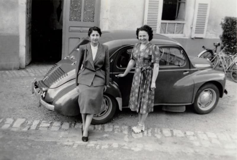 Two French ladies posing with a Renault 4 CV in front of the family home, 1955