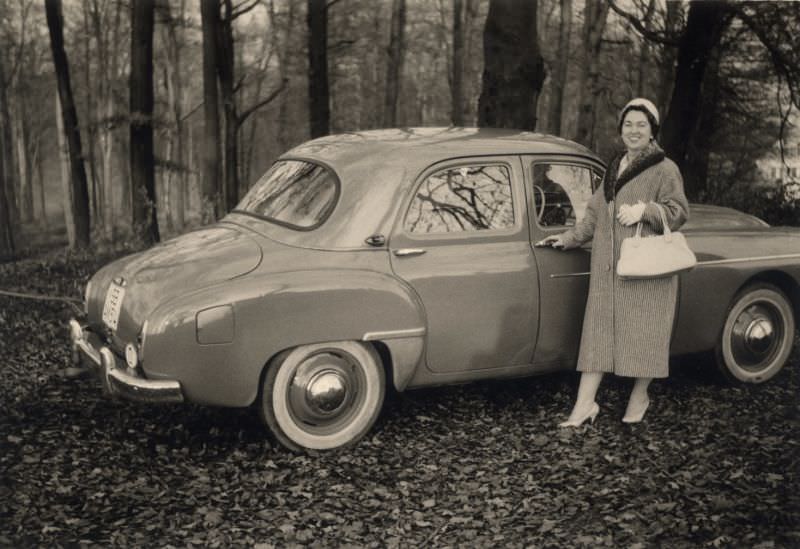 A middle-aged lady posing with a Renault Frégate in wintertime.