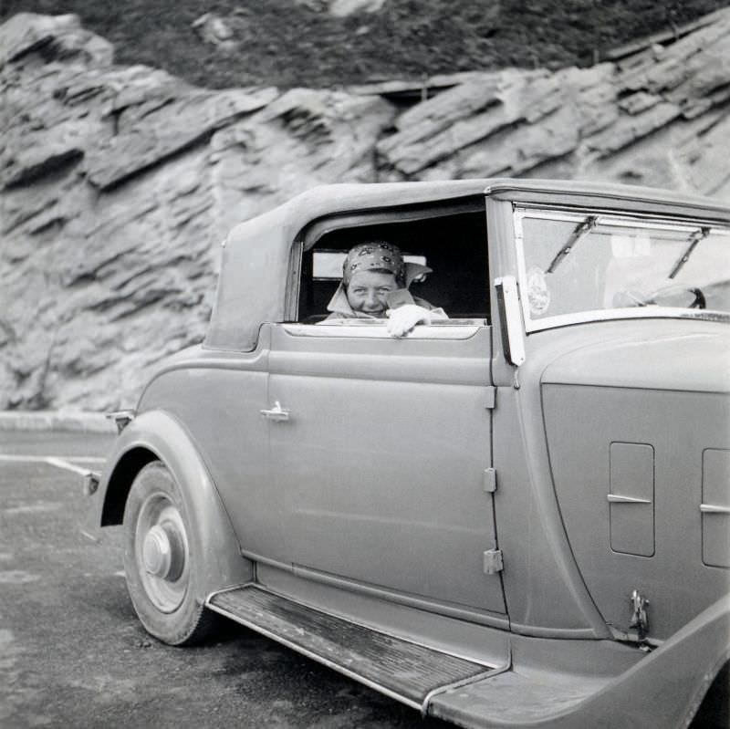An elegant lady posing in the passenger seat of a Renault Monaquatre Cabriolet-Spider convertible on a mountain road, 1935