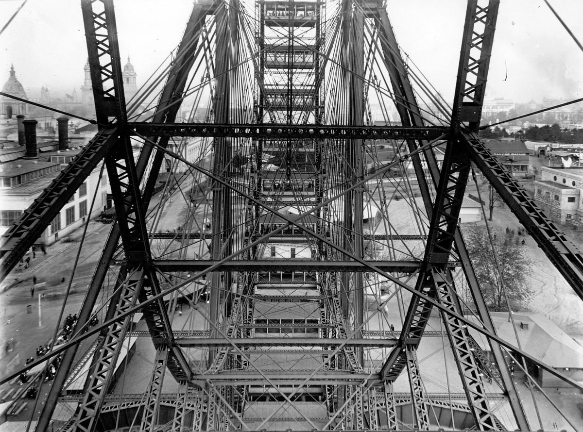 A view of the fairgrounds, seen though the Ferris wheel from one of its cars