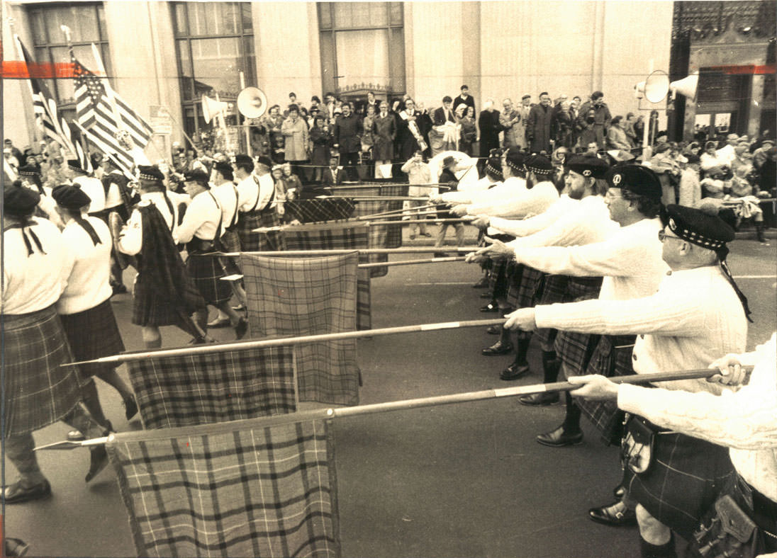 Step lively, me lads! Members of this Irish marching unit dip their flags in salute as they pass the reviewing stand on Cathedral street in yesterday’s St. Patrick’s Day parade. March 1979.