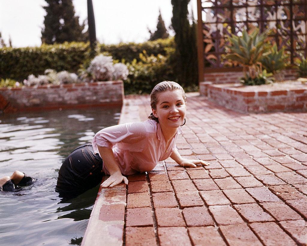 Tuesday Weld emerging, fully-clothed from a swimming pool, 1960.