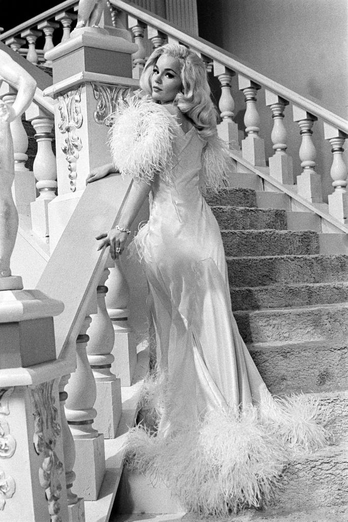 Tuesday Weld in a white satin dress with white feathers, 1963.
