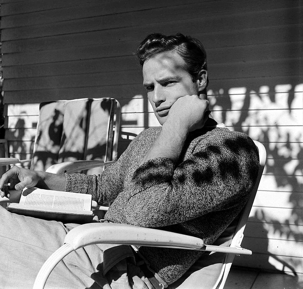 Marlon Brando reads a book during a break in filming 'The Men', 1949.