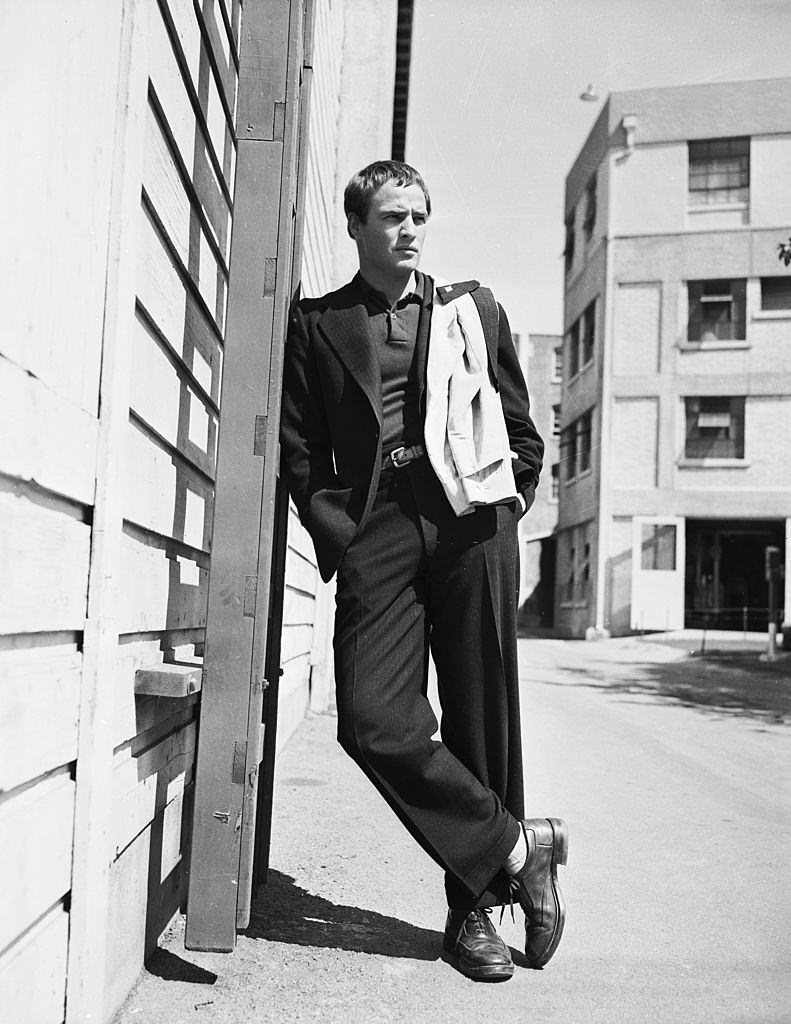 Marlon Brando leaning against a ladder on the side of a building, 1952.