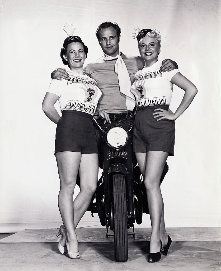 Marlon Brando on Motorcycle and Posing with young Women, 1955.