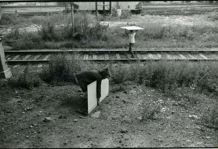 Two children carrying boards over the railroad tracks by the Jefferson Park Housing Project, Jefferson Park, 1974