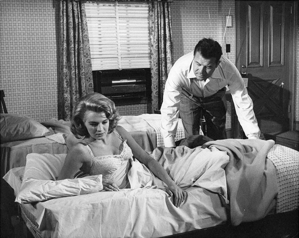 Angie Dickinson and Jack Carson in a motel room scene from the film 'The Bramble Bush', 1960.