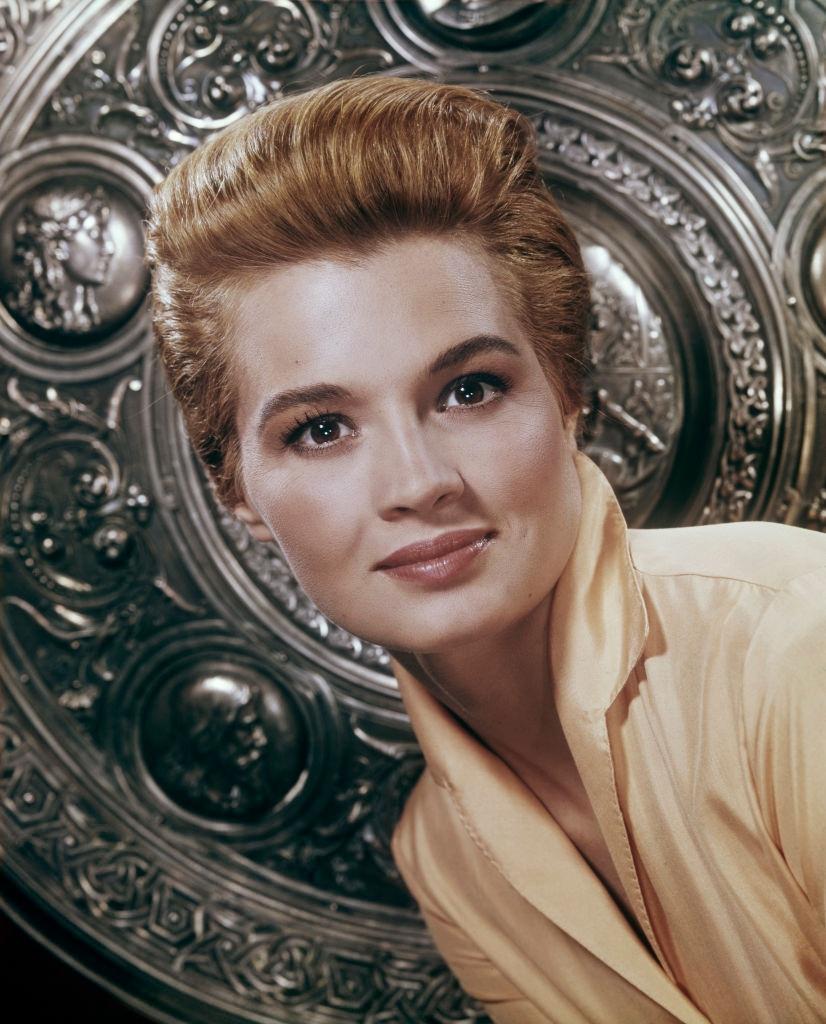 Angie Dickinson in front of an embossed shield, 1960.