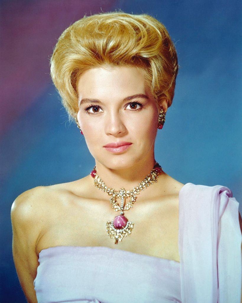 Angie Dickinson wearing a shoulderless gown and necklace with ornate pendant, 1960.