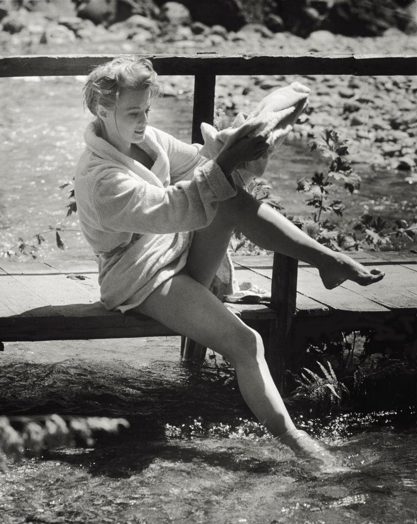 Angie Dickinson drying herself with a bathrobe after swimming, 1961.