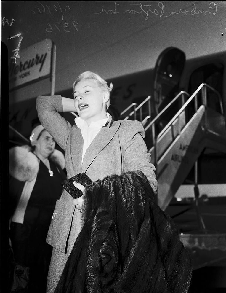 Barbara Payton waiting for the arrival of Franchot Tone, 1951.