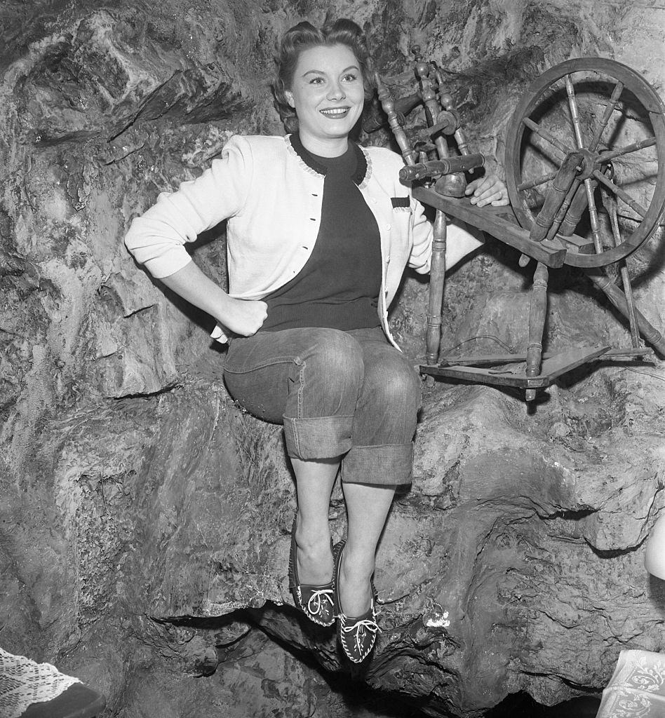 Barbara Payton poses by a spinning wheel on the set of the movie, 1952.