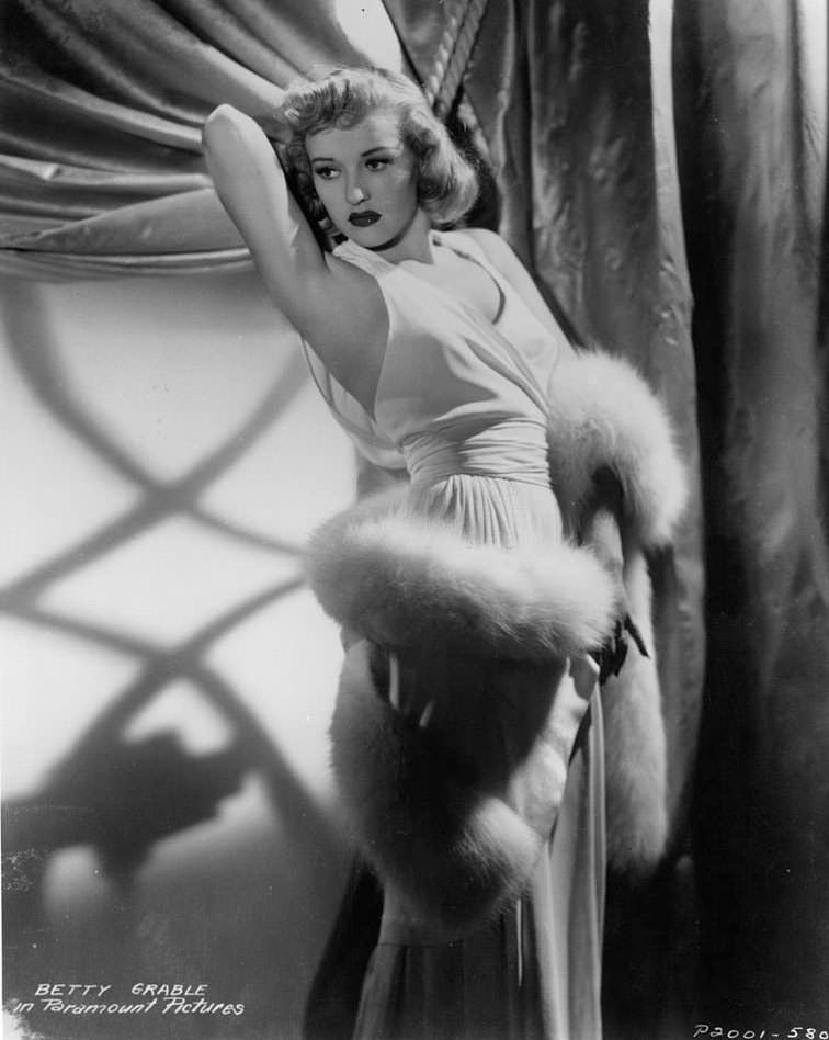 Betty Grable in an evening gown and a white fur wrapped around her body, 1935.