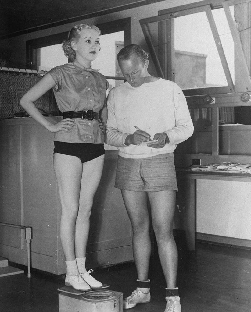 Betty Grable is weighed by her personal trainer, 1936.