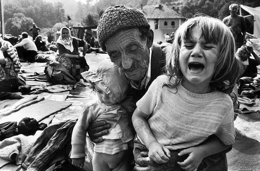 A Muslim grandfather holds his exhausted, crying granddaughters on his lap after a long, frightening journey on foot to a United Nations refugee camp at Kladanj.