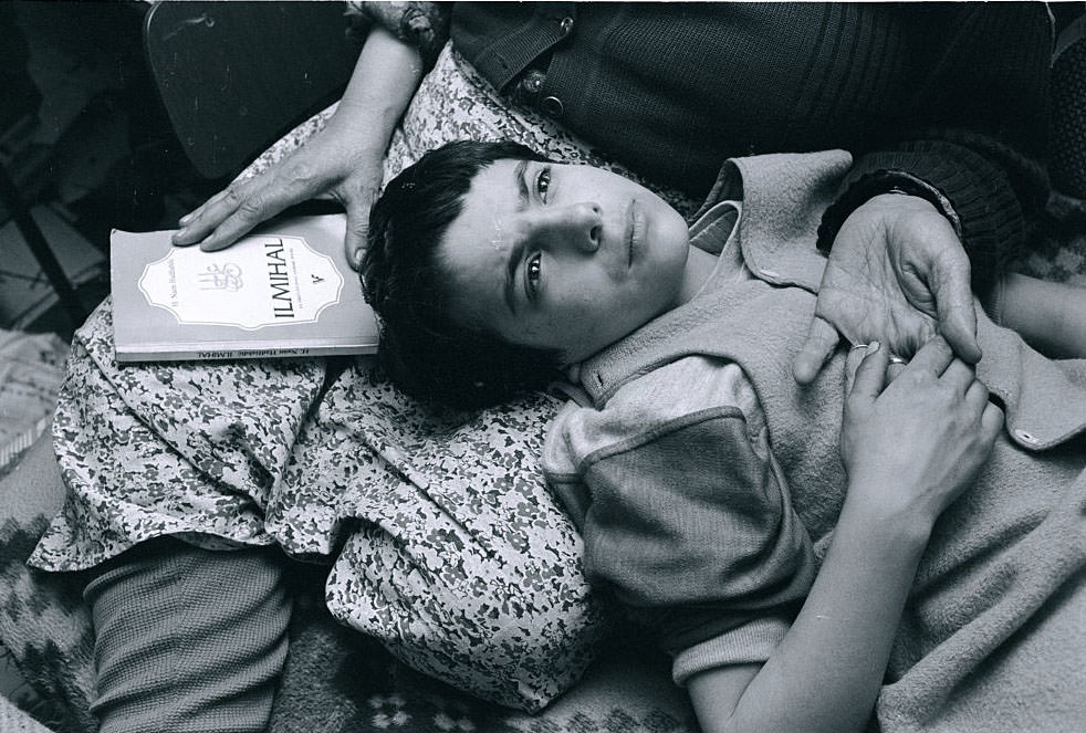 Mirza Mangajic, a 10-year-old Muslim boy, lays his head in his grandmother's lap as he prays with her.