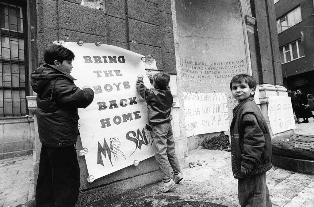 Boys putting up a poster saying 'Bring the boys back home' as part of a peace demonstration in Sarajevo, 1994.