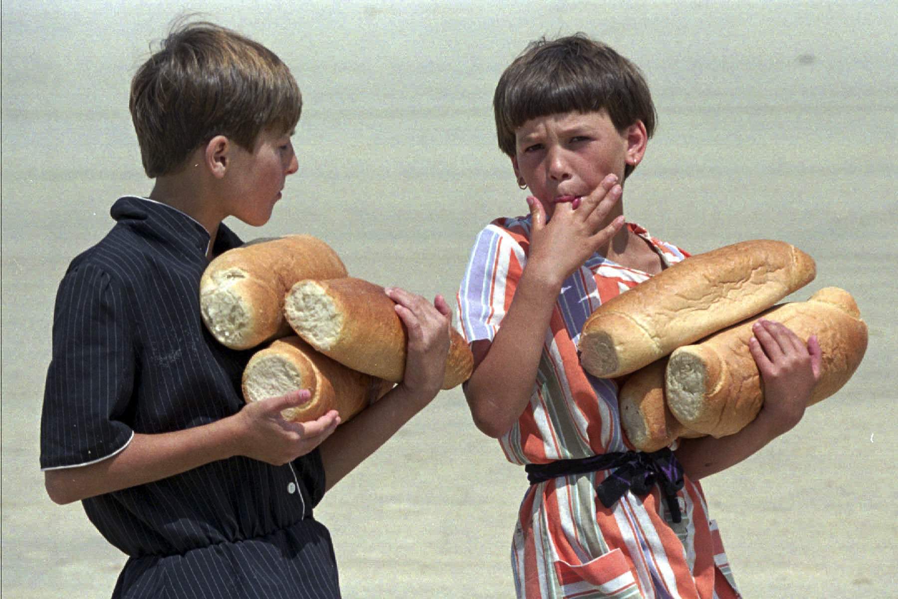 Bosnian refugee children from Srebrenica, carry loaves of bread, which they received from the United Nations at the refugee camp at Tuzla airport, July 19, 1995.