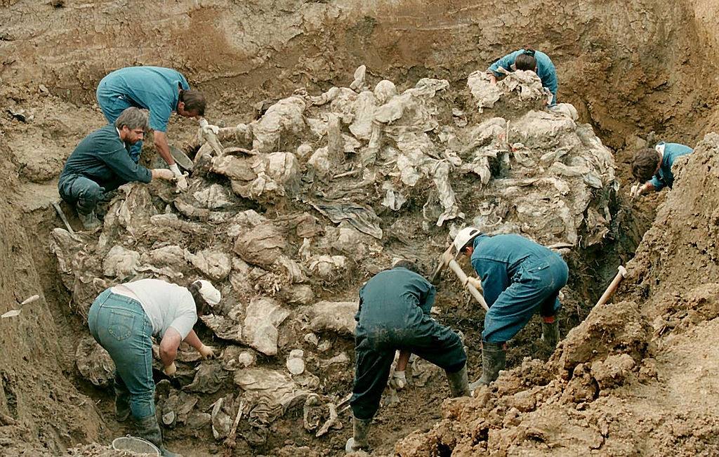 Forensic experts from the International war crimes tribunal in the Hague works on a pile of partly decomposed bodies, 24 July 1996 found in a mass grave in the village of Pilica some 300 km northeast of Sarajevo.