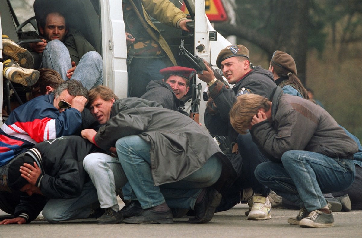 A Bosnian special forces soldier returns fire in downtown Sarajevo as he and civilians come under fire from Serbian snipers, on April 6, 1992.