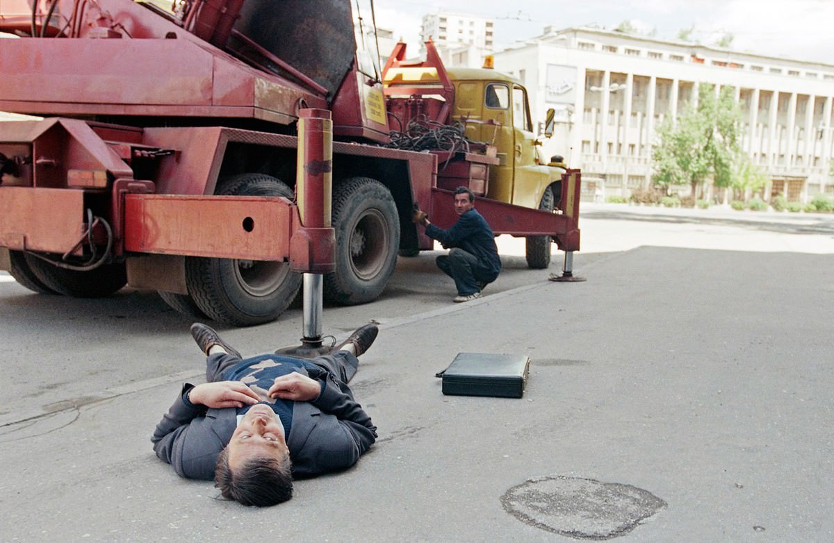 A man takes cover behind a truck while looking at the body of Rahmo Seremet, 54, a Sarajevo engineer working for the city, after he was shot dead by a sniper.