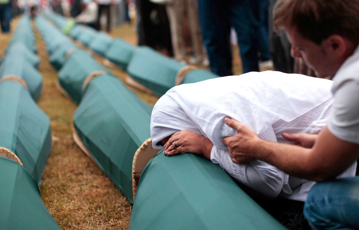 A Bosnian Muslim woman cries on the coffin of a relative during a mass funeral for victims killed during 1992-1995 war in Bosnia