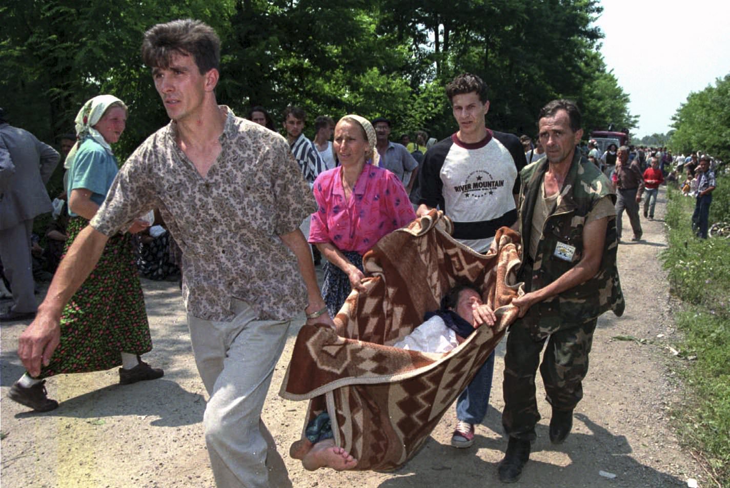 Refugees and a Bosnian government soldier carry a sick woman on a makeshift stretcher to a hospital inside a U.N. base outside Tuzla, July 13, 1995.