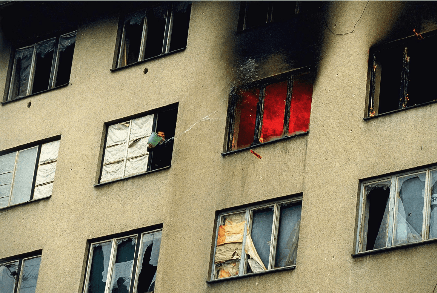 A Serb man attempts to put out a fire that was caused by Serb arsonists in the Sarajevo suburb Grbavica, Bosnia, 1996.