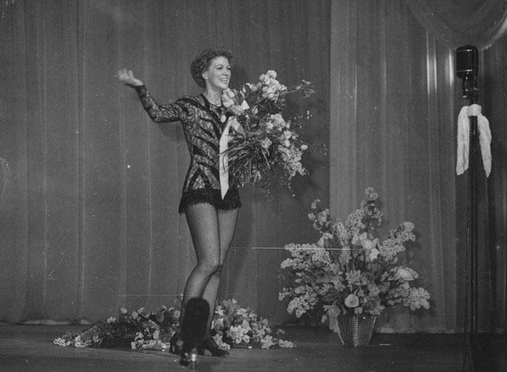 Eleanor Powell holding a bouquet of flowers following a performance on the stage, March 21st 1949.