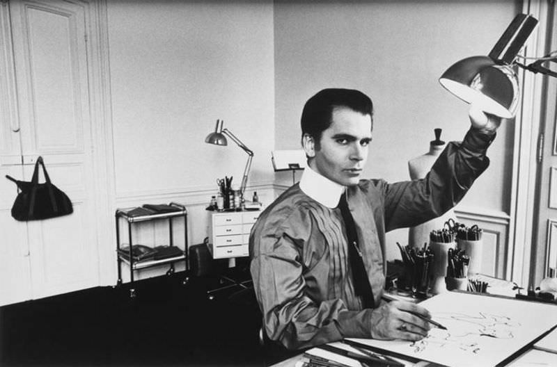 Karl Lagerfeld arranging the dark veil of an evening dress around the neck of a model, 1959.