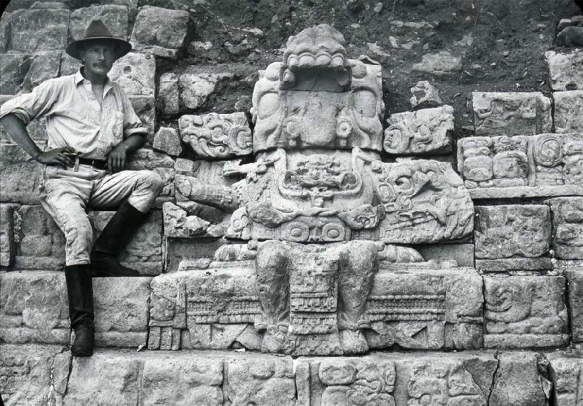 George Gordon sits next to a figure seated on a throne on the Hieroglyphic Stairway, Copan, Honduras, 1900.