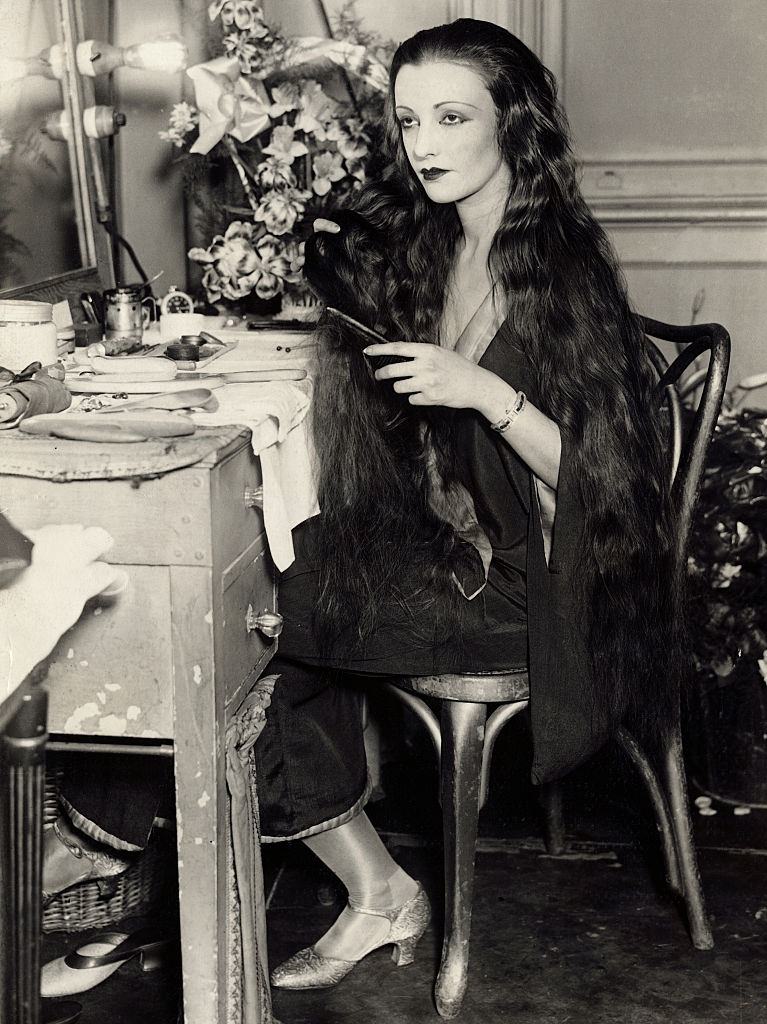 Natacha Rambova combing her long black tresses during an interview, 1927.