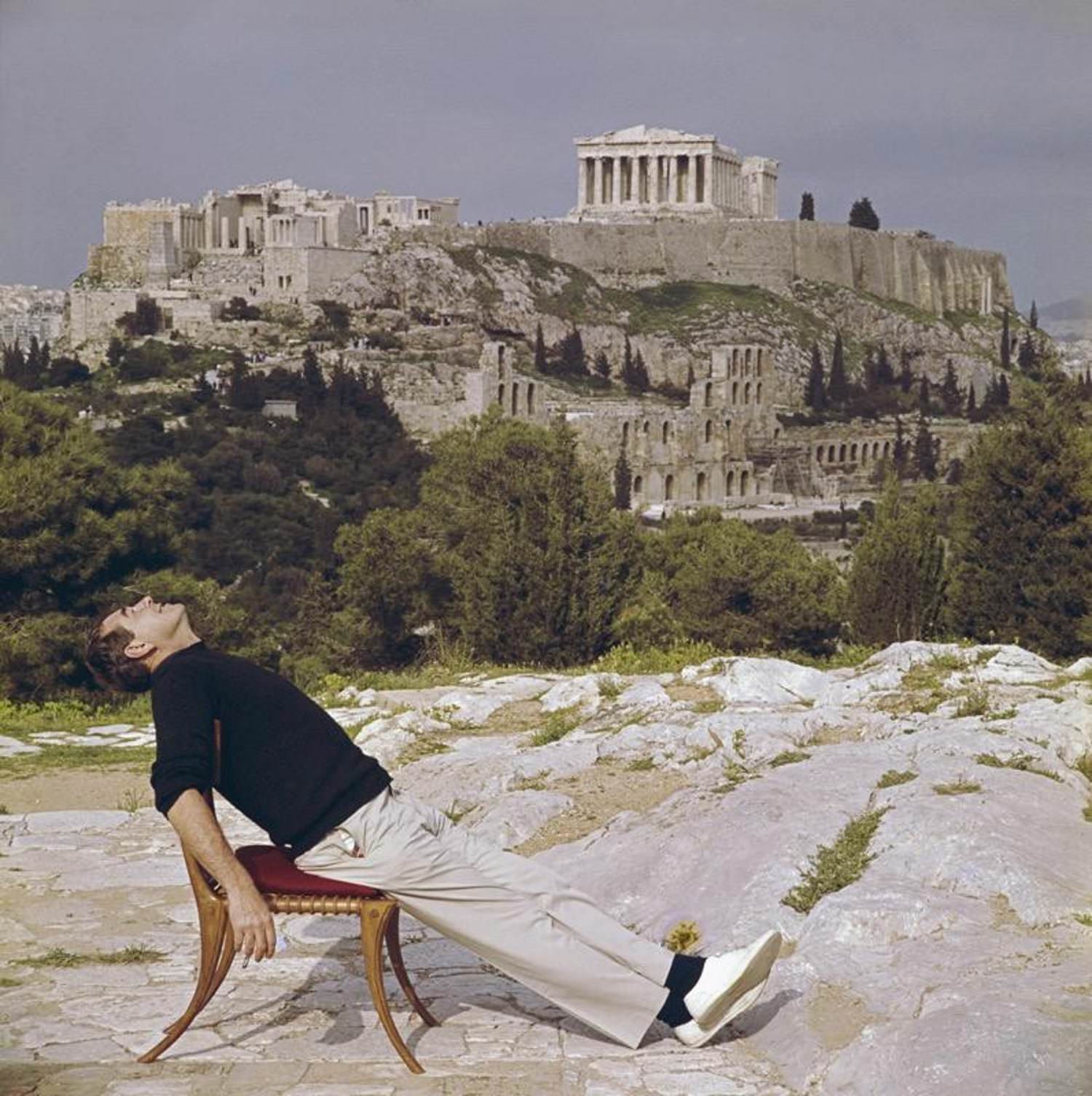 Photographer Slim Aarons slouches in a chair with the Acropolis and its surroundings as a backdrop, 1955.
