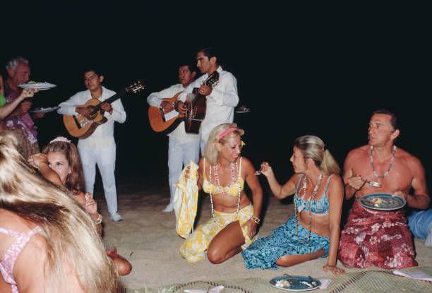 American singer Dinah Shore (center) and actor Kirk Douglas (far right) at a beach party in Acapulco, Mexico, January 1968