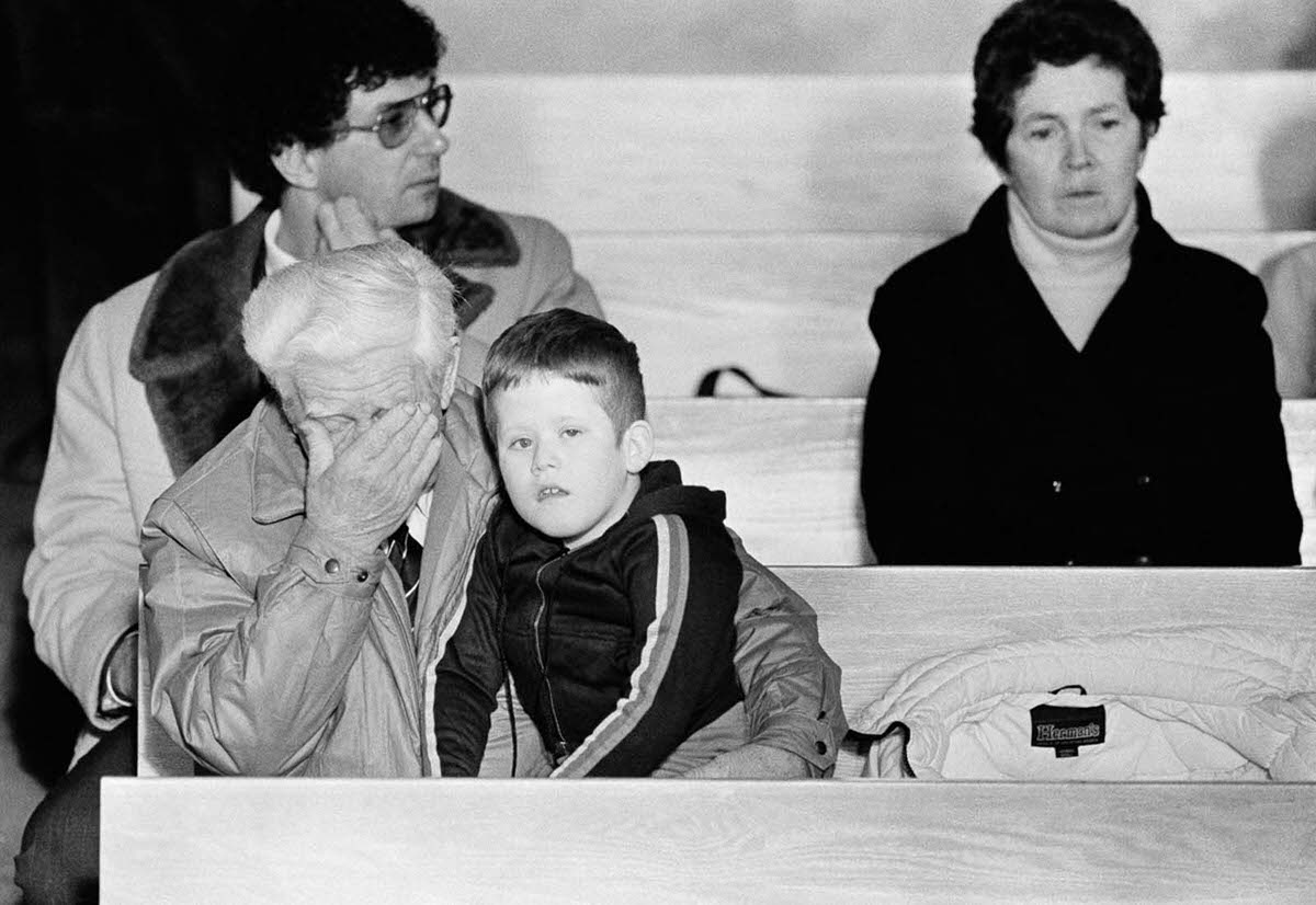 Billy Gifford rubs his eyes while holding his grandson Jimmy Stillman, 8, during a memorial service for Christa McAuliffe at a church in Concord, New Hampshire. Jan. 29, 1986.